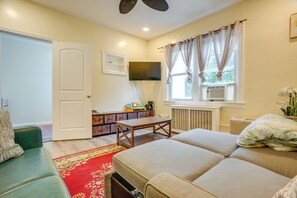 A room with a sofa, a table, a TV, and a window with curtains. - Near Shops & Transit to NYC! Yonkers Apt (Yonkers)