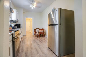 A kitchen with a stainless steel refrigerator, wooden cabinets, a built-in oven, and a dining area with a table and chairs. - Near Shops & Transit to NYC! Yonkers Apt (Yonkers)