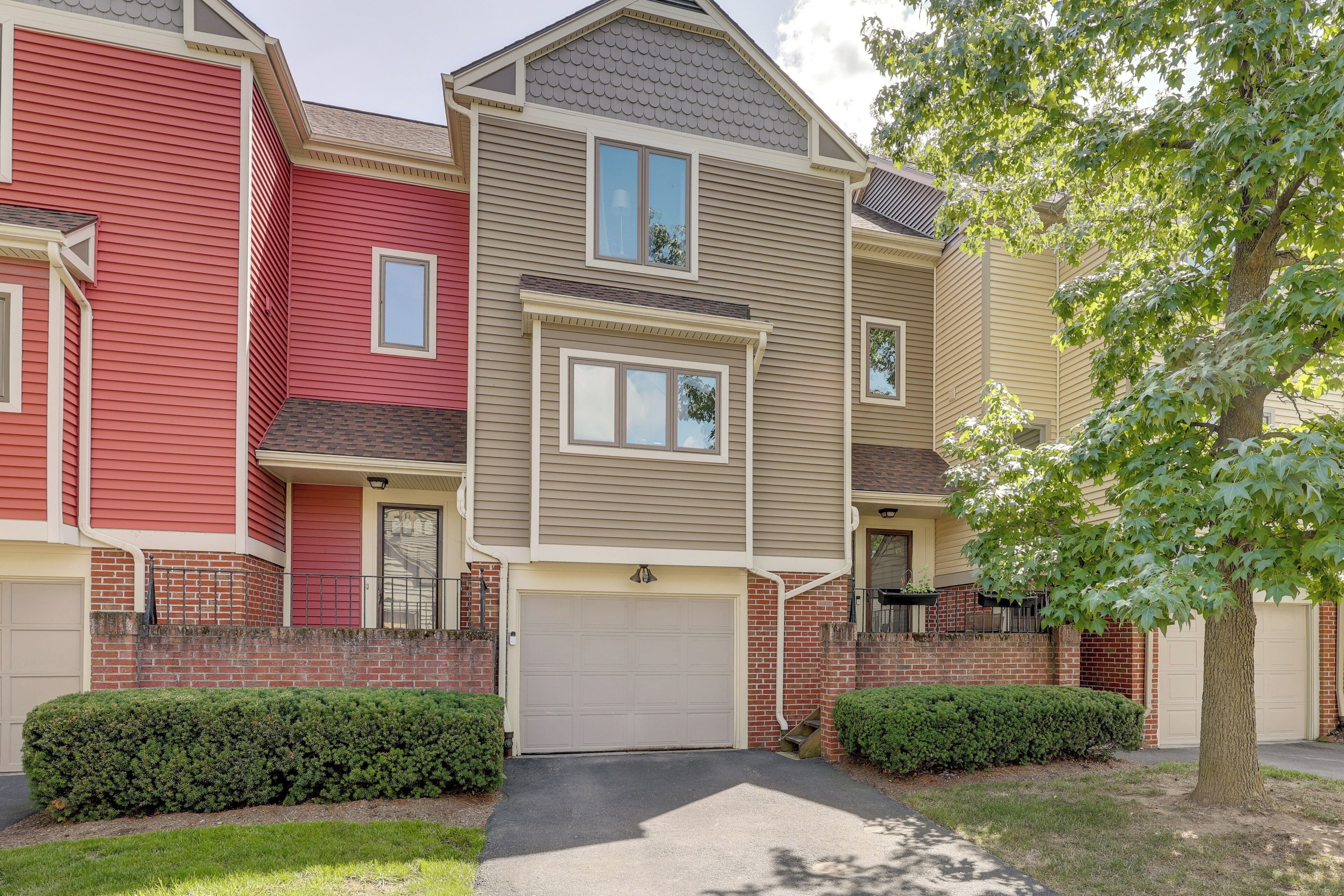A row of townhouses with a garage, brick facade, and a well-maintained lawn.