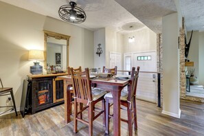 A dining area with a wooden table and chairs, a chandelier, and a kitchen in the background. - Home Gym & Office! Townhome Walk to Genesee River (Rochester)