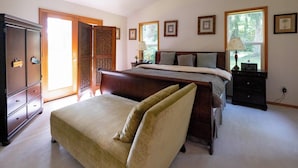 Un dormitorio con cama, cómoda, mesita de noche y ventana con vista a árboles.
