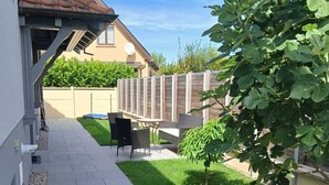 Ein gepflasterter Weg führt zu einer Terrasse mit Gartenmöbeln.