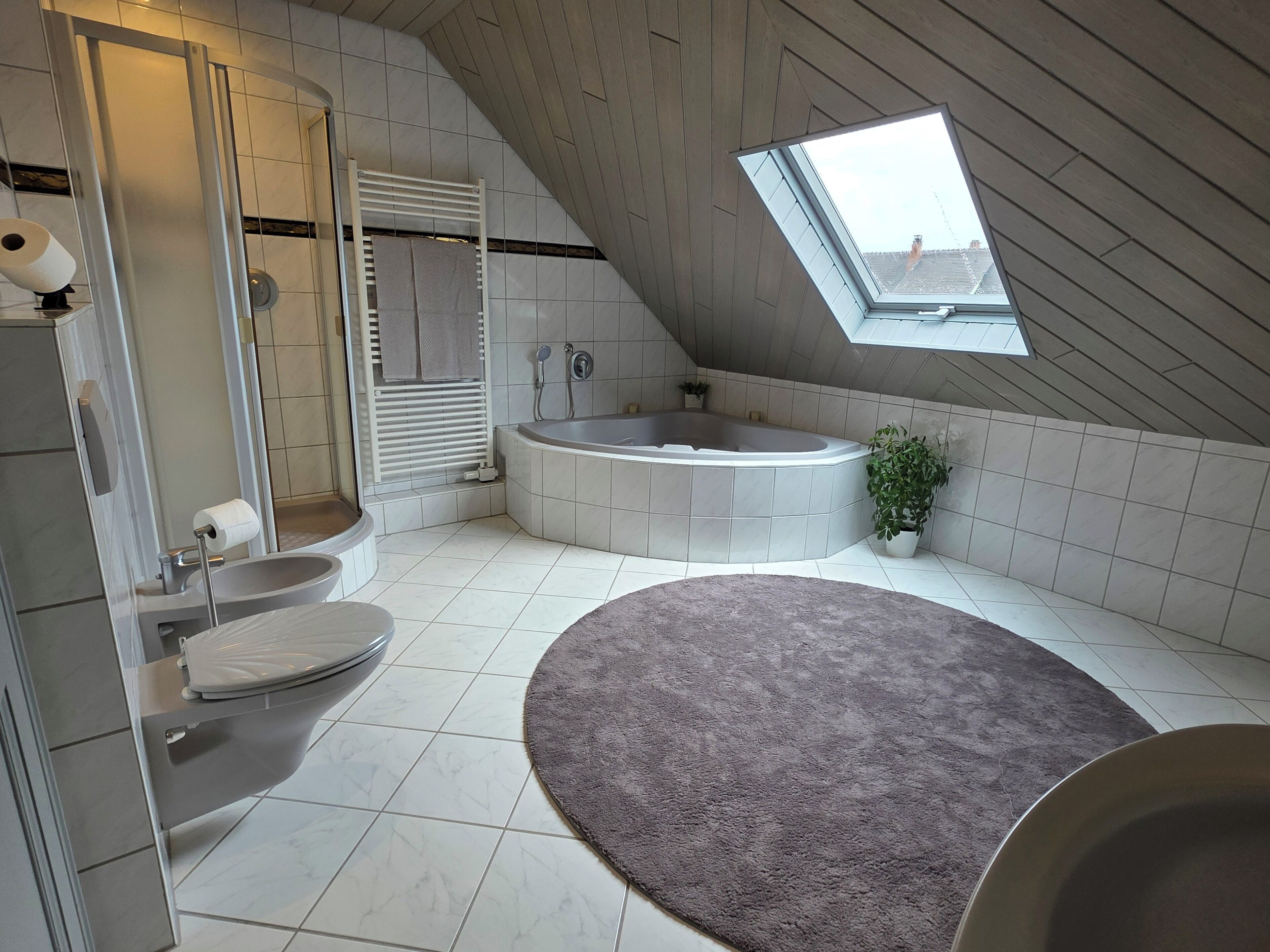 Een moderne badkamer met een vrijstaand bad, een toilet en een douchehoek.