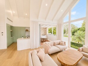 Un salon moderne avec un canapé, une table basse ronde et une vue sur l’extérieur.