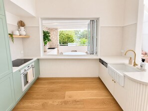 Eine moderne Küche mit integriertem Fenster, weißen Schränken und Holzboden.