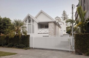 Ein Haus mit weißer Fassade, einer Steinsäule und einem weißen Zaun.