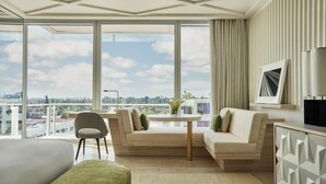 A hotel room with a large window, a sofa, a small table, and a bed. - Four Seasons Hotel at The Surf Club.  (Surfside)