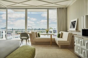 Habitació d'hotel amb una finestra gran, un sofà, una taula petita i un llit.