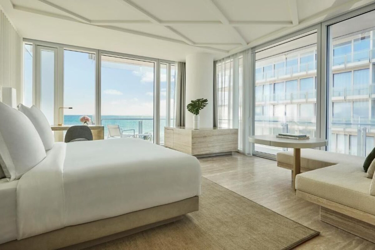 Habitació d'hotel moderna amb un llit gran, zona de seients i vista a l'oceà.