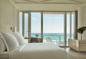 Una habitació d'hotel amb un llit gran, una taula, una cadira i vista a l'oceà.