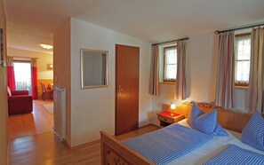 A bedroom with a bed, bedside table, lamp, and curtains. - Vrbo Property (Berchtesgaden)