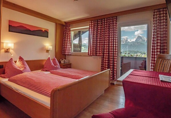 A hotel room with a bed, a table, and a view of mountains. - Vrbo Property (Berchtesgaden)