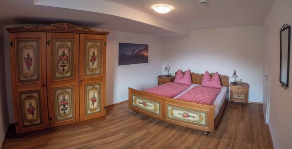 A bedroom with a wooden bed, a wardrobe, a nightstand, a bedside table, and a painting on the wall. - Vrbo Property (Berchtesgaden)