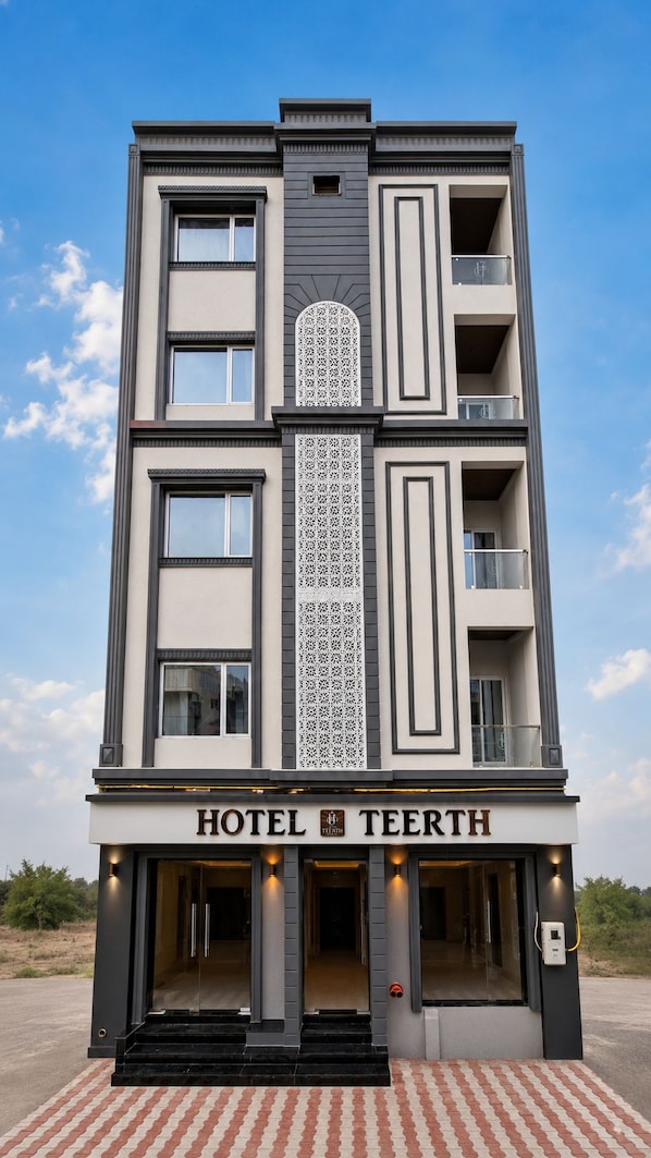 A multi-story hotel with a modern facade, balconies, and a clear sky. - Hotel Teerth Dwarka (Dwarka)