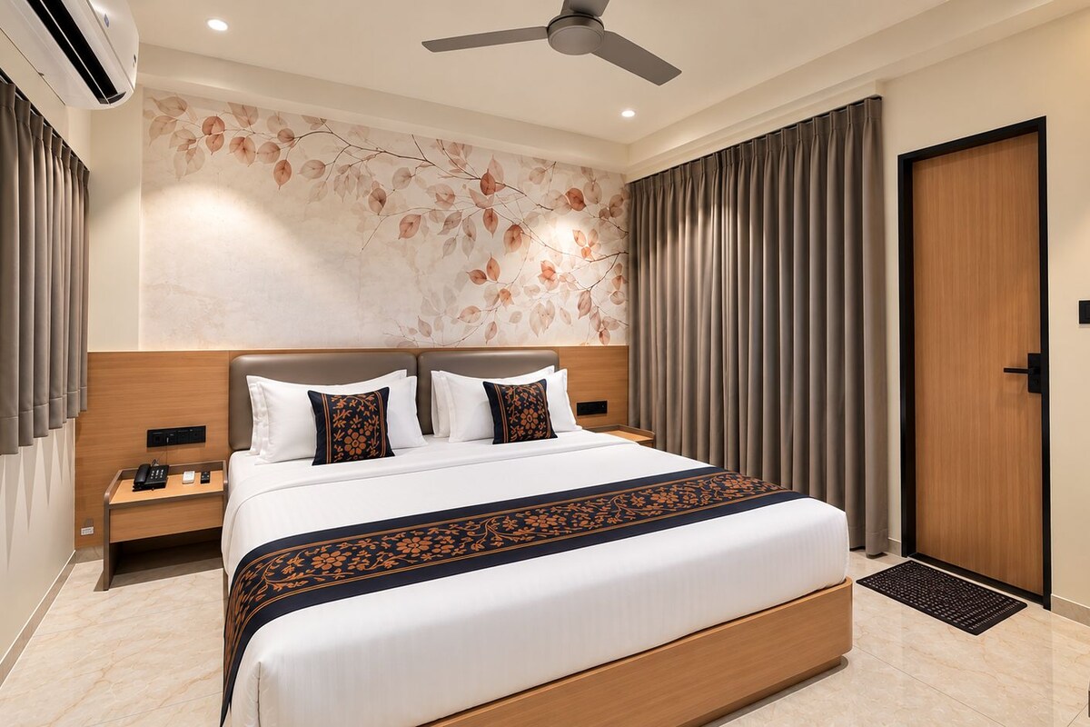 Habitación de hotel con una cama grande, una mesita de noche con teléfono, aire acondicionado de pared y ventilador de techo.