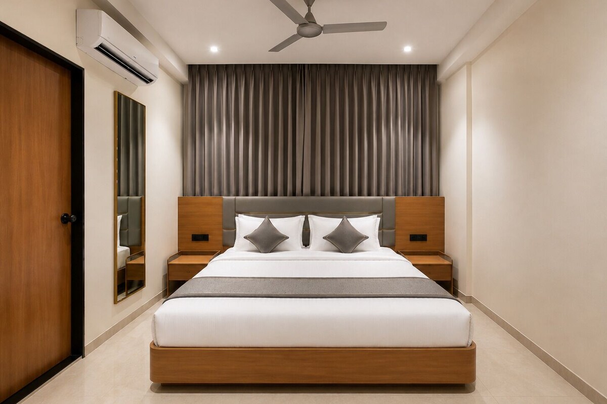 A modern hotel room with a large bed, two bedside tables, a ceiling fan, and a large window with curtains.