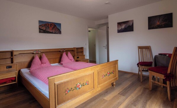 A bedroom with a wooden bed, a chair, and two paintings on the wall. - Vrbo Property (Berchtesgaden)