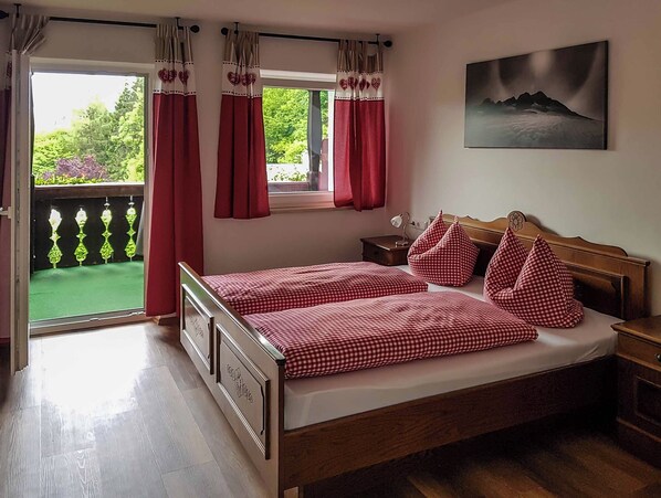 A bedroom with a double bed, a nightstand, a window with curtains, and a painting on the wall. - Vrbo Property (Berchtesgaden)