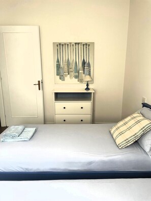A bedroom with a bed, a nightstand with a lamp, a wall-mounted artwork, and a door. - Casa Indaco – Lake View, terrace & relax (Padenghe sul Garda)