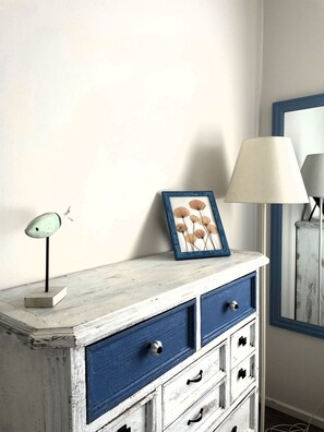 A white dresser with blue drawers and a picture frame on top. - Casa Indaco – Lake View, terrace & relax (Padenghe sul Garda)