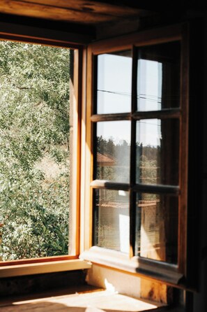 A window with a view of a garden and a building with a tiled roof. - Stone house in the hills of the Livradois (Marsac-en-Livradois)