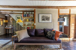 Ein gemütliches Wohnzimmer mit einem dunkelgrauen Sofa, einem Bücherregal und einer städtischen Stadtansicht als Bild.