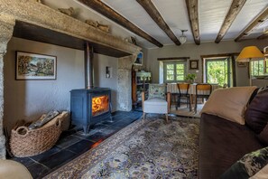 Ein gemütliches Wohnzimmer mit Kamin aus Stein, einem Essbereich mit Tisch und Stühlen sowie einem großen Fenster, das für natürliches Licht sorgt.