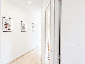 A hallway with three framed cityscape posters on the wall, a door on the right, and a carpeted floor. - Apartment La Cala Blanc in Cala Del Moral (Rincón de la Victoria)