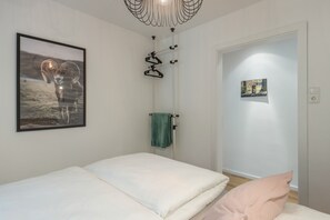Une chambre à coucher comprenant un lit, un porte-serviettes et une porte donnant sur une autre pièce.