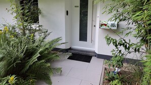 A white building with a door, a window, and a sign on the wall.