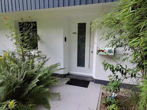 A white building with a door, a window, and a sign on the wall.
