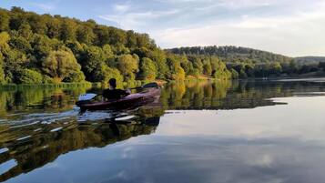 Ein ruhiger See mit einem einzigen Boot, das an der Küste vor Anker liegt, umgeben von dichtem Wald.