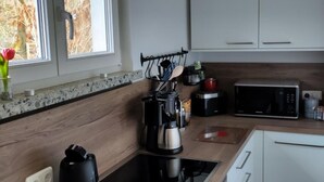 A modern kitchen with a black stove, white cabinets, and a window with a view of trees.