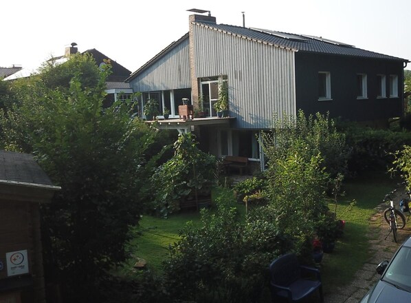 Ein Wohngebäude mit Balkon, umgeben von Grünpflanzen und einem Fahrrad.