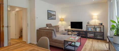 Ein modernes Wohnzimmer mit einer Couch, einem Couchtisch, einem Fernseher und einem Bücherregal.