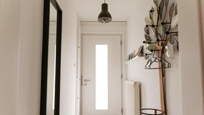 A hallway with a white door, a radiator, and a wall-mounted plant holder.