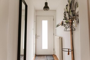 A hallway with a white door, a radiator, and a wall-mounted plant holder.