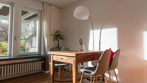 Un coin repas avec une table en bois, des chaises, une plante et un lampadaire.