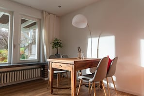 Ein Essbereich mit Holztisch, Stühlen, einer Pflanze und einer Stehlampe.