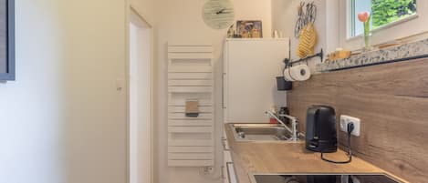 Una cocina compacta con horno empotrado, lavamanos y cafetera.