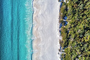 An aerial view of a beach with clear turquoise waters and a sandy shore. - Sage by Hyams Beach Seaside Cottages | Romantic, iconic heritage cottage (Hyams Beach)