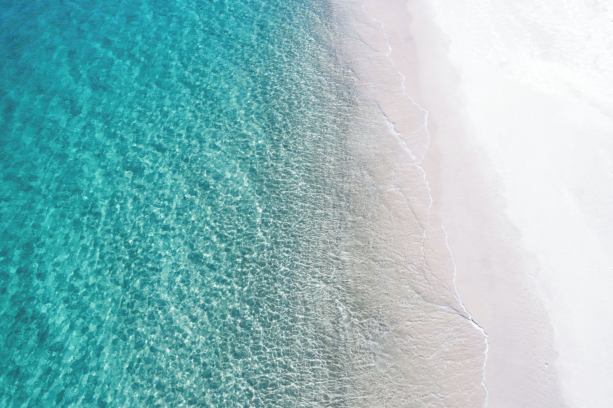 A beach with clear turquoise water and white sand.