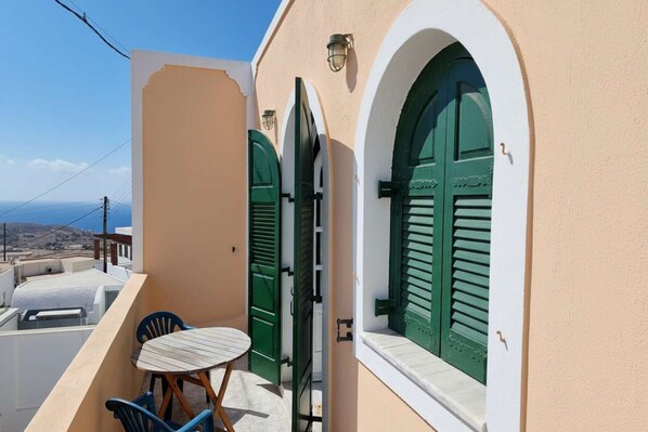 A balcony with a table and chairs, a green door, and a view of the sea. - Akrotiri Flat near Red Beach (akrotiri)
