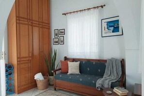 A cozy living room with a wooden wardrobe, a sofa with patterned cushions, a potted plant, and a framed picture on the wall. - Akrotiri Flat near Red Beach (akrotiri)