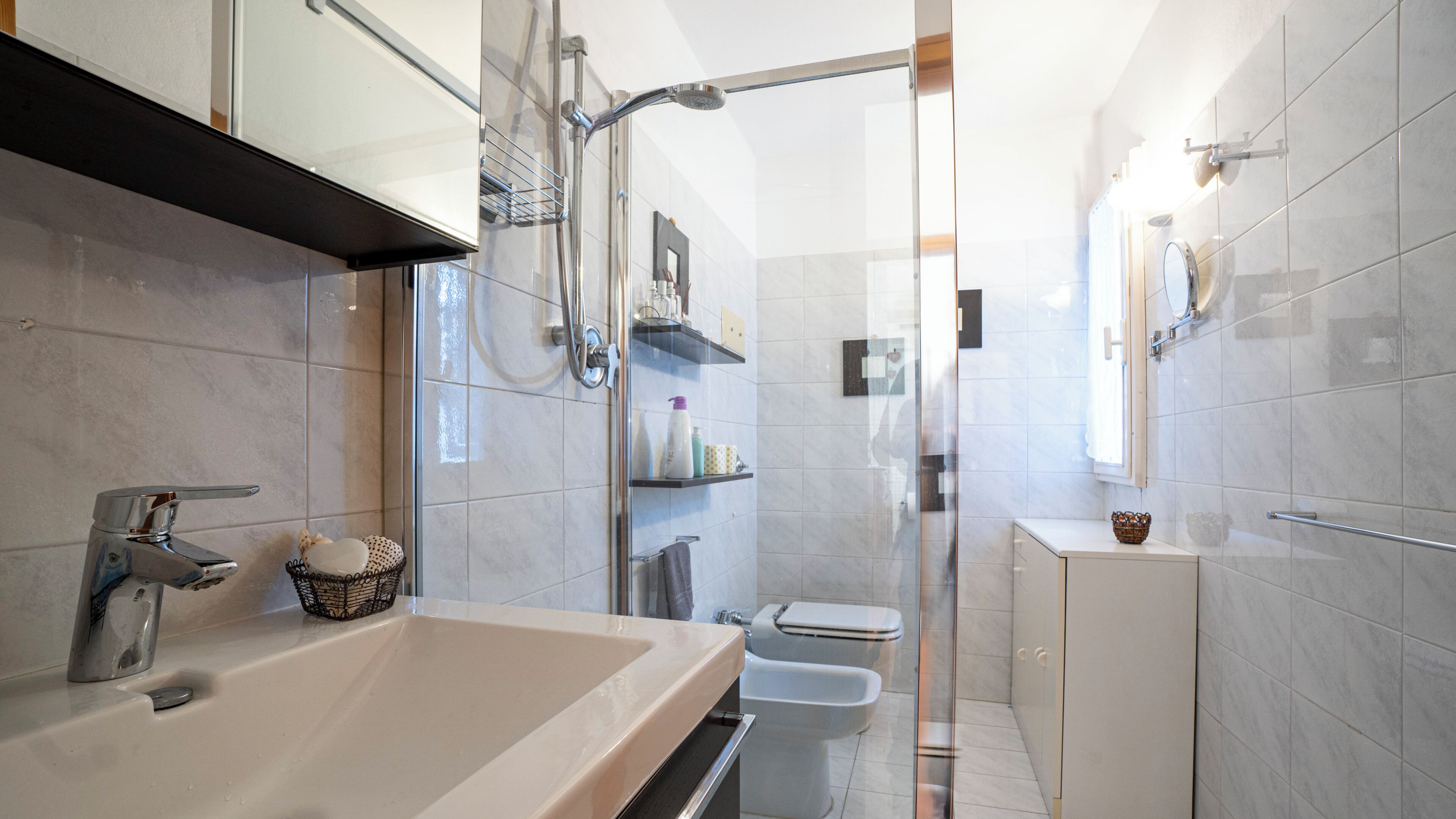Un baño moderno con un lavamanos grande, cabina de ducha con vidrio y un inodoro.