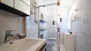 Un baño moderno con un lavamanos grande, cabina de ducha con vidrio y un inodoro.