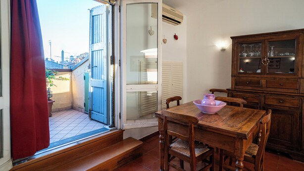 Un comedor con una mesa de madera, sillas, un armario con puertas de vidrio y un ventanal corredero que da a un espacio exterior.