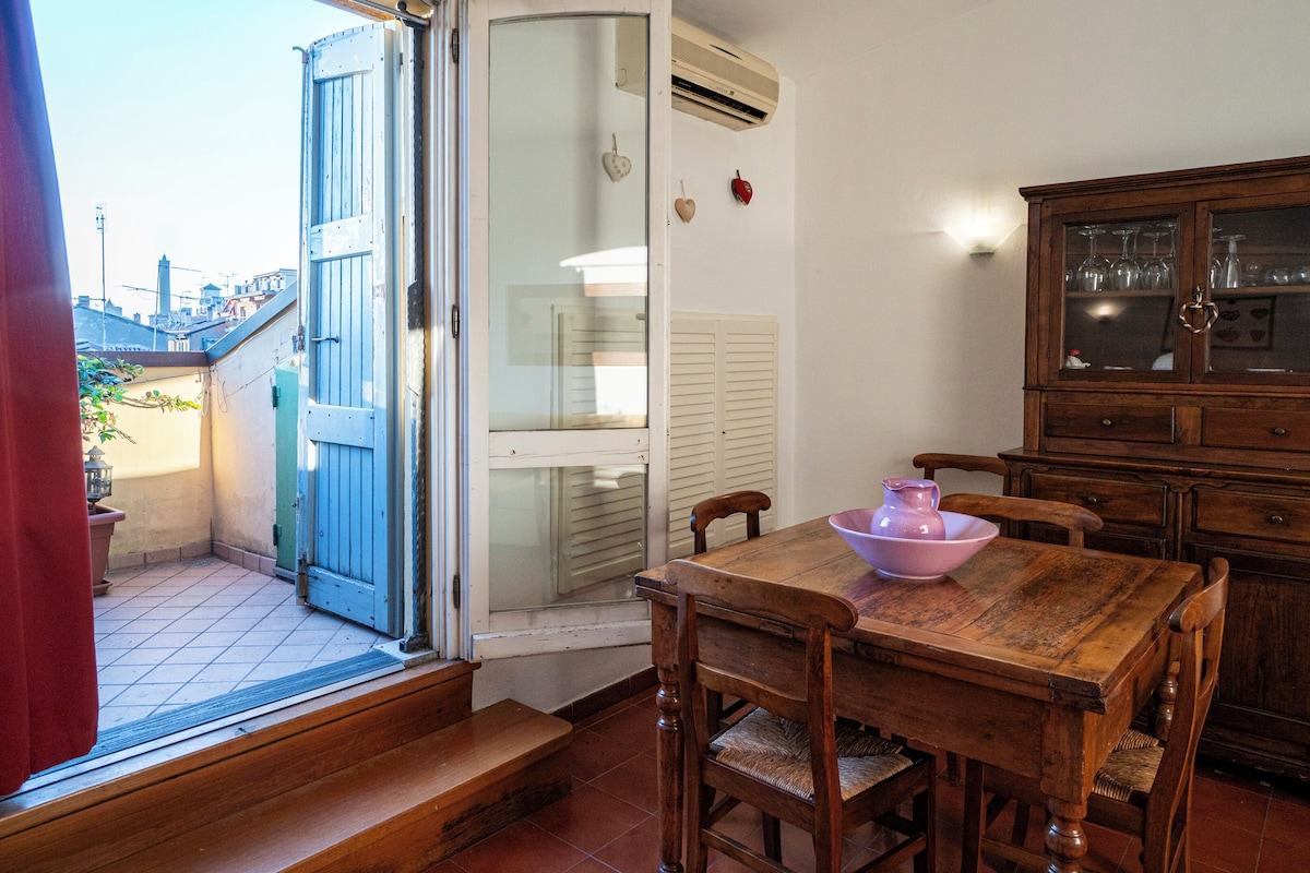 Un comedor con una mesa de madera, sillas, un armario con puertas de vidrio y un ventanal corredero que da a un espacio exterior.