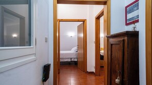 A hallway leading to a bedroom with a bed, a wooden cabinet, and a framed picture on the wall. - San Petronio Vecchio 57 (Bologna)