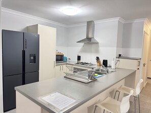 A modern kitchen with a built-in refrigerator, microwave, and stove. - Blissful Haven (Perth)